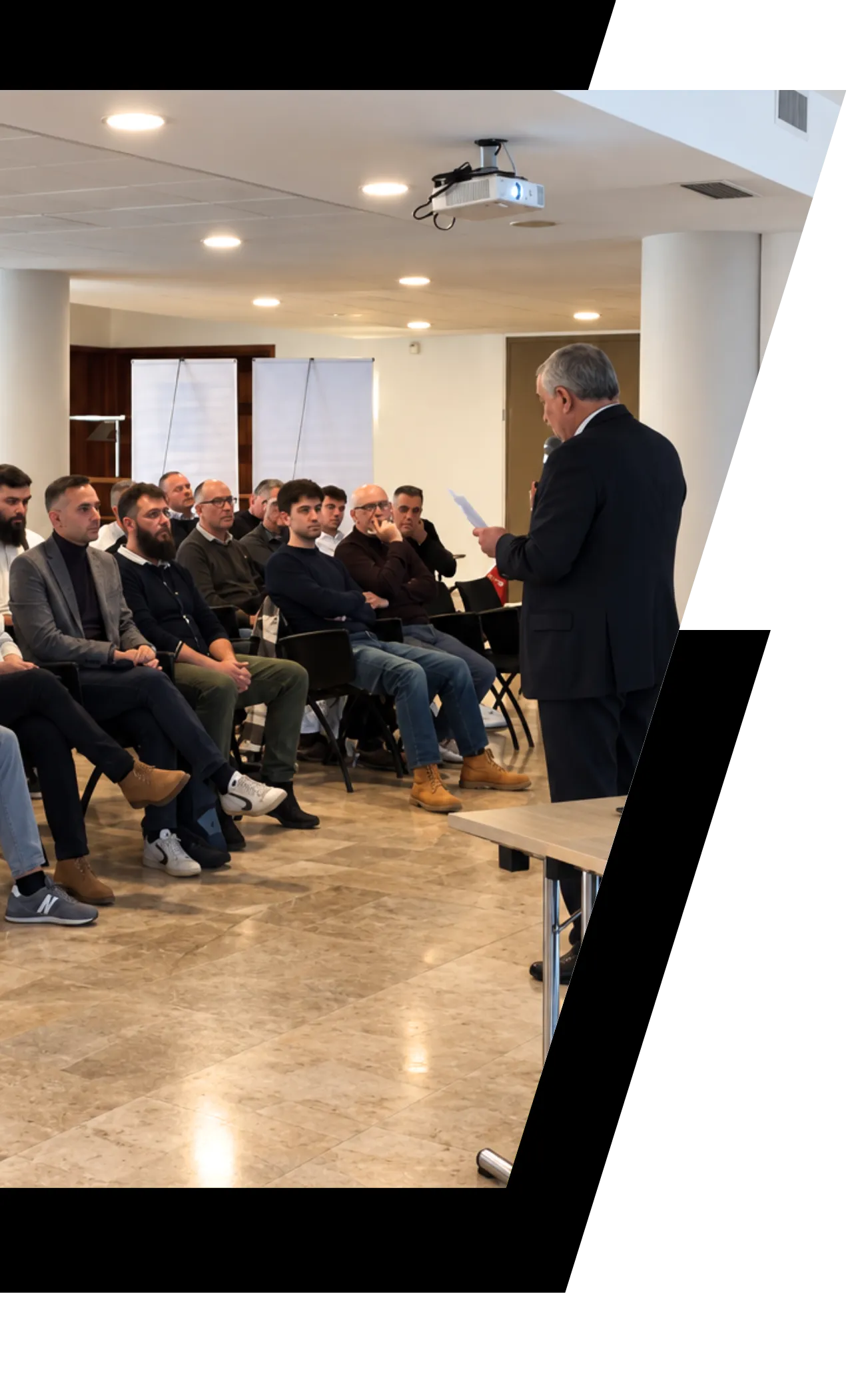 Fotografia del testo della pagina About us, sala di Tech Drive Solutions con presentazione ad un uditorio